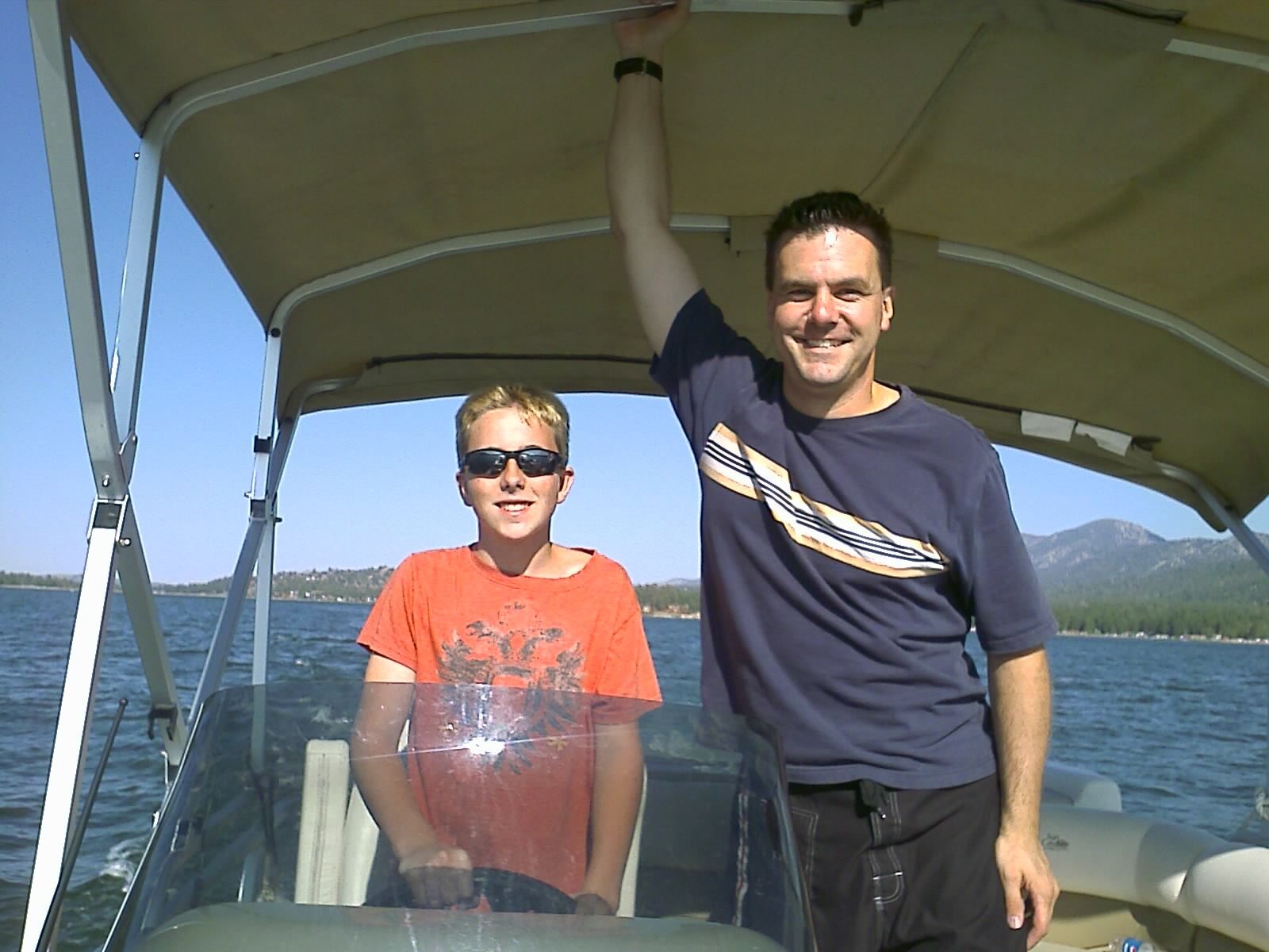 Roger and one of his sons smiling on a boat at Big Bear Lake