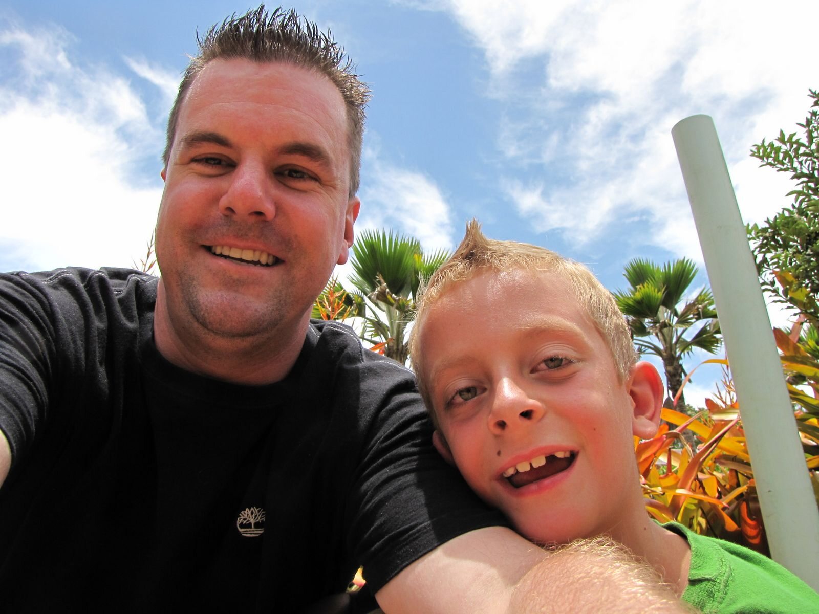 Roger and one of his sons smiling beside tropical plants on Oahu