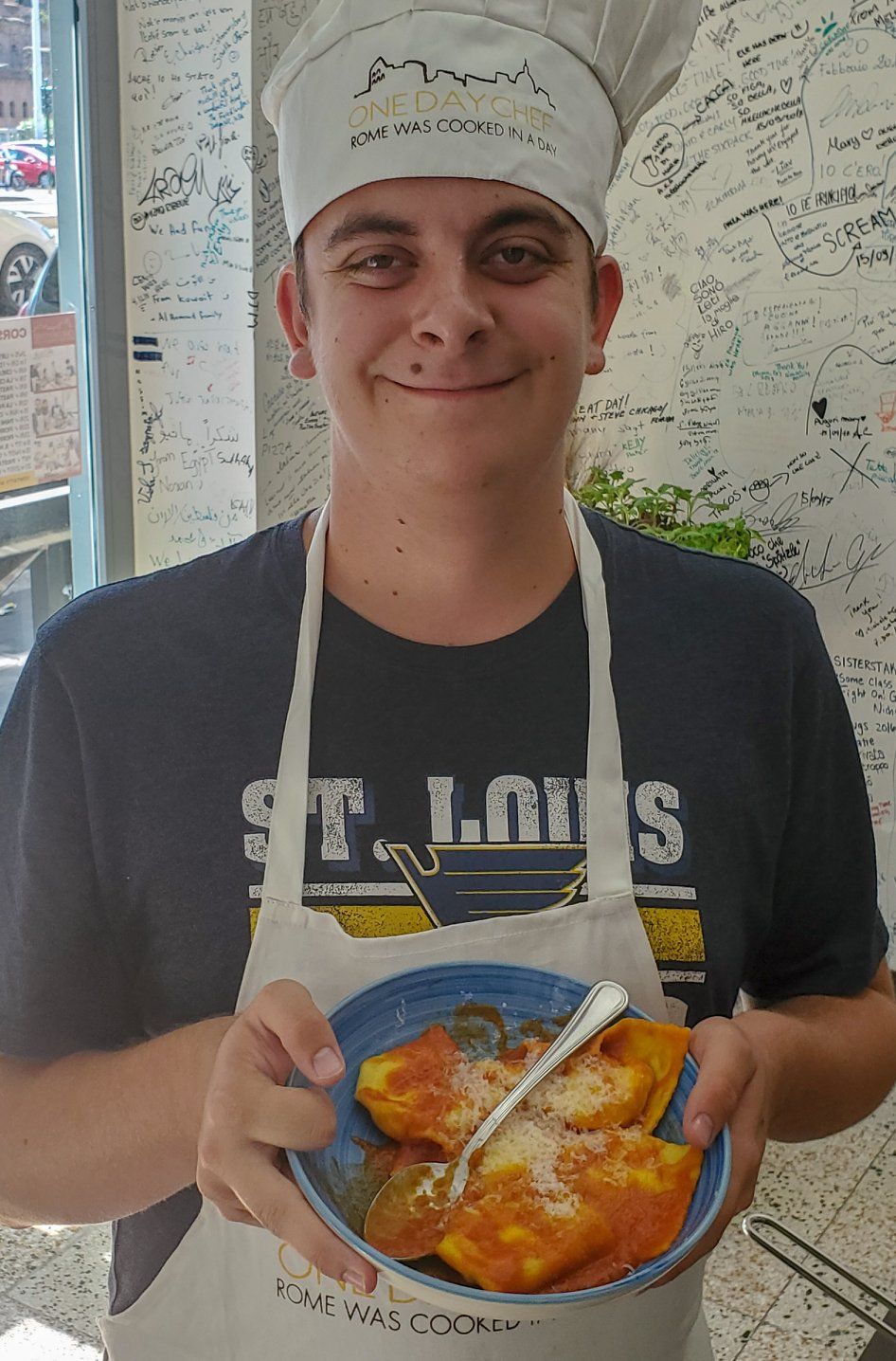 One of Roger's sons wearing a chef hat with a plate of pasta