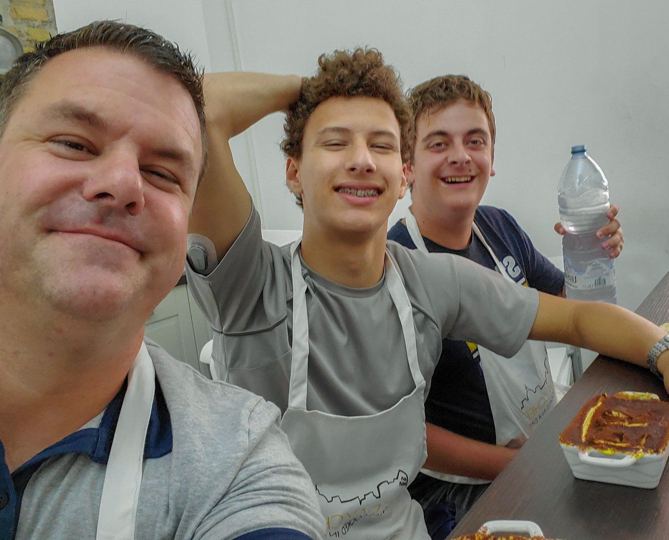 Roger and his sons smiling at a cooking class in Rome