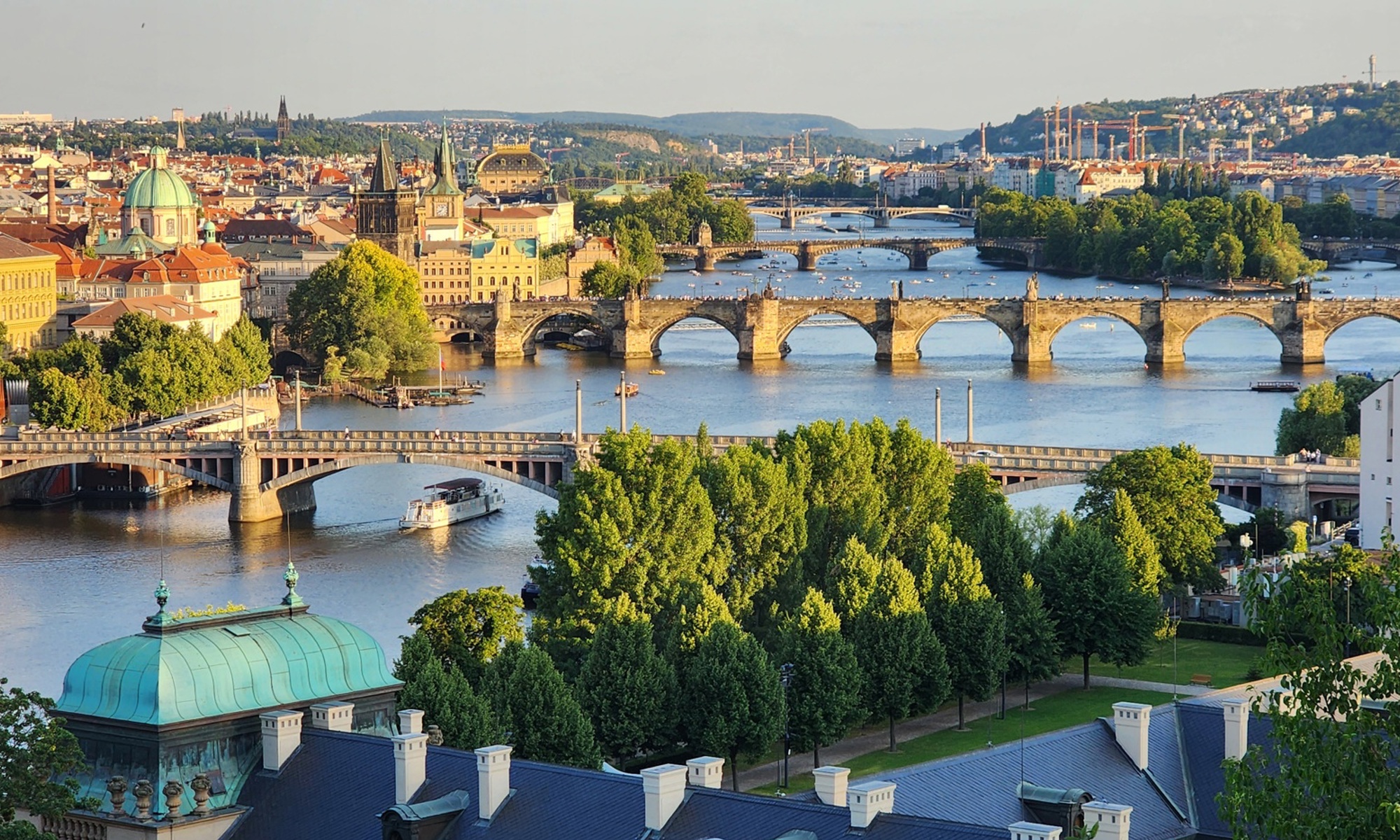 Prague rooftops and bridges along the Vltava River in warm evening light